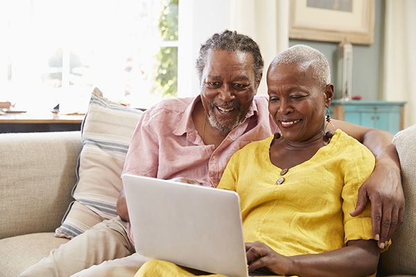 Image depicts a couple on a sofa looking using Patient Access online at home